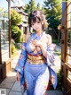 A woman in a blue kimono standing in front of a door.