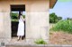 A woman in a white dress standing in a doorway.