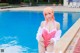 A woman in a pink bathing suit standing next to a swimming pool.