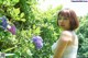 A woman in a white dress standing in front of a bush.