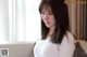 A woman in a white sweater sitting on a bed.