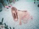 A woman in a pink bunny costume crouching on a bed of white pebbles.