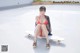 A woman in a bikini sitting on a skateboard.