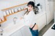 A woman standing in a kitchen next to a sink.