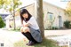 A young woman sitting on the ground next to a tree.