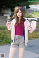 A young woman holding a baseball bat on a street.