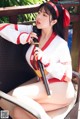 A woman in a red and white outfit holding a sword.