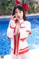 A woman in a red and white outfit posing by a pool.