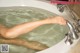 A woman's feet in a bathtub with water coming out of it.
